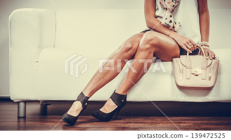 Fashionable girl with handbag sitting on sofa Fashionable girl with handbag sitting on sofa 139472525