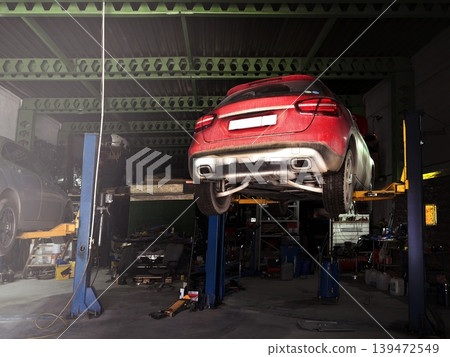 Red suv car in the service hangs on the lift. Oil change, diagnostics photo Red suv car in the service hangs on the lift. Oil change, diagnostics photo 139472549