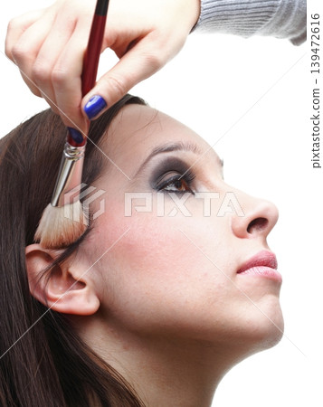 beautiful young brunette woman applying powder with a brush beautiful young brunette woman applying powder with a brush 139472616
