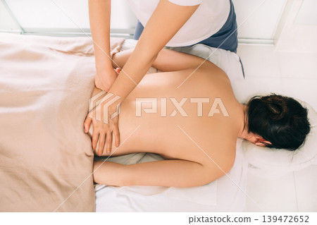 Top view of woman lying on a massage table and receive back massage, spa weekend Top view of woman lying on a massage table and receive back massage, spa weekend 139472652