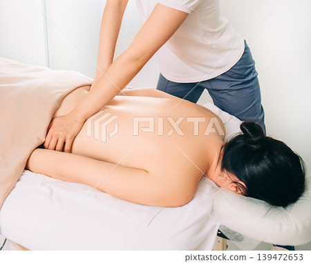 Top view of woman lying on a massage table and receive back massage, spa weekend Top view of woman lying on a massage table and receive back massage, spa weekend 139472653