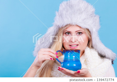 Woman in winter hat drinking from mug Woman in winter hat drinking from mug 139472774