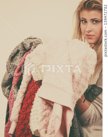 Woman holding big piles of clothing Woman holding big piles of clothing 139472782