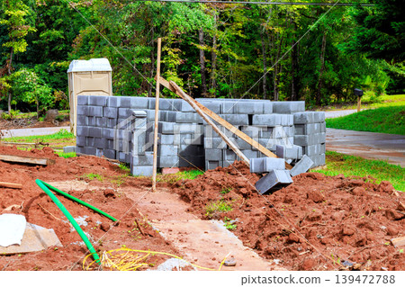 Stacks concrete blocks to form wall in forested area with tools debris around. Stacks concrete blocks to form wall in forested area with tools debris around. 139472788