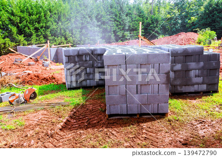 Workers prepare construction site with stacked building cement cinder blocks Workers prepare construction site with stacked building cement cinder blocks 139472790