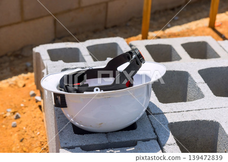Hard hat over on concrete blocks at construction site under construction work is ongoing nearby. Hard hat over on concrete blocks at construction site under construction work is ongoing nearby. 139472839