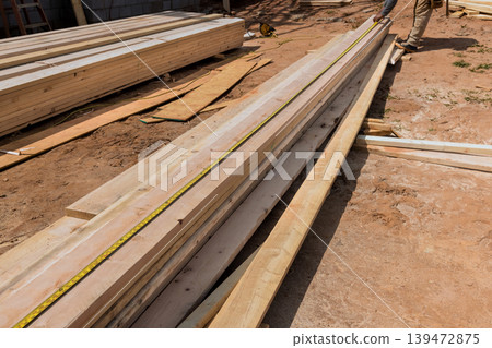 Workers are busy measuring organizing wooden planks on construction site under works area Workers are busy measuring organizing wooden planks on construction site under works area 139472875