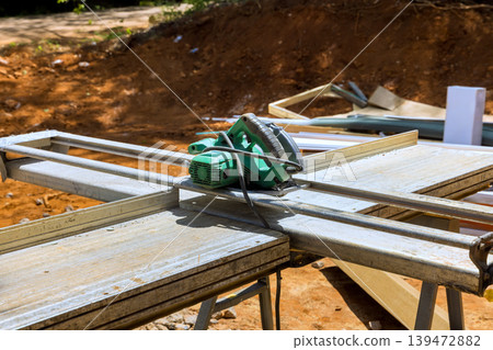 Power hand saw is placed on work table at a construction site with various materials tools nearby Power hand saw is placed on work table at a construction site with various materials tools nearby 139472882