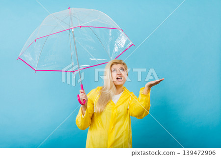 Woman wearing raincoat holding umbrella checking weather 139472906