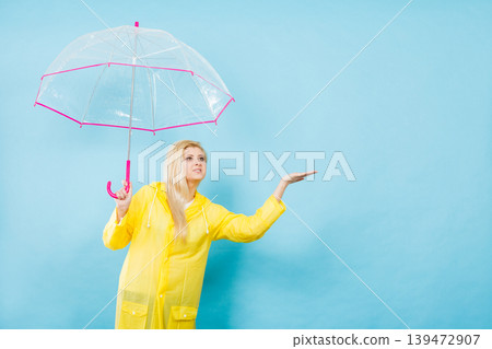 Woman wearing raincoat holding umbrella checking weather Woman wearing raincoat holding umbrella checking weather 139472907