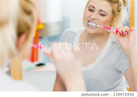 Woman brushing cleaning teeth in bathroom Woman brushing cleaning teeth in bathroom 139472939