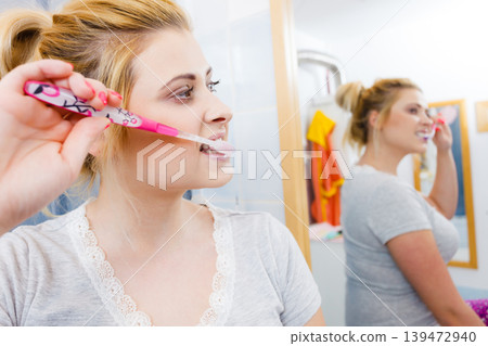 Woman brushing cleaning teeth in bathroom Woman brushing cleaning teeth in bathroom 139472940
