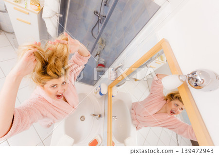 Woman looking at her very tangled blonde hair 139472943