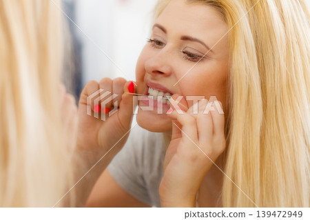 Woman cleaning her teeth using dental floss Woman cleaning her teeth using dental floss 139472949