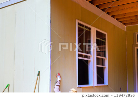 Worker is applying installing siding to t outside wall of house during home improvement task Worker is applying installing siding to t outside wall of house during home improvement task 139472956