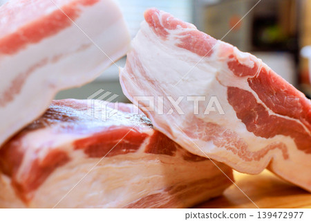 Several pieces of pork raw belly are on wooden surface in kitchen ready for meal preparation. Several pieces of pork raw belly are on wooden surface in kitchen ready for meal preparation. 139472977