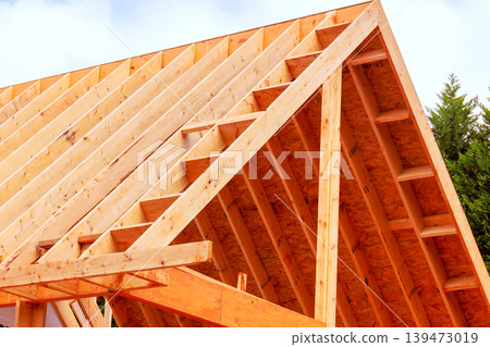 Workers are installing wooden beams to build roof frame at construction site 139473019