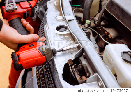 Service auto mechanic is fixing car broken with screwdriver tool in garage setting Service auto mechanic is fixing car broken with screwdriver tool in garage setting 139473027