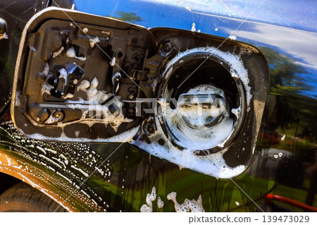 Service worker cleans fuel tank opening on vehicle with soap water while standing outside Service worker cleans fuel tank opening on vehicle with soap water while standing outside 139473029