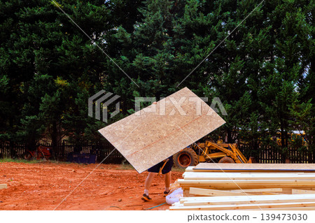 Contractor is moving large plywood at construction site during new home project Contractor is moving large plywood at construction site during new home project 139473030