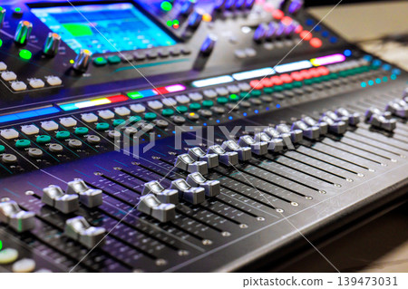 Sound worker is adjusting mixing console while working on music project in recording studio Sound worker is adjusting mixing console while working on music project in recording studio 139473031