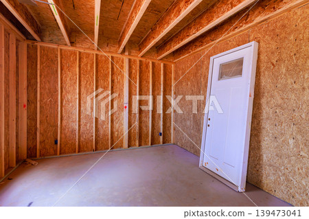 Workers prepare new room where walls are framed, door stands against wall waiting to be installed. Workers prepare new room where walls are framed, door stands against wall waiting to be installed. 139473041