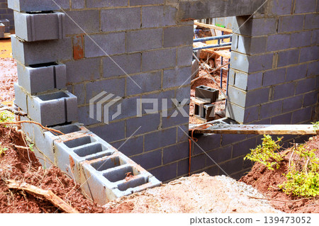 Workers are building walls with concrete blocks at construction site in an outdoor setting. Workers are building walls with concrete blocks at construction site in an outdoor setting. 139473052