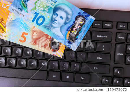New Zealand banknotes on keyboard sit together on desk in an office setting New Zealand banknotes on keyboard sit together on desk in an office setting 139473072