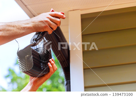 Worker works on fixing gutter system on house under assembling installing gutter channels 139473100