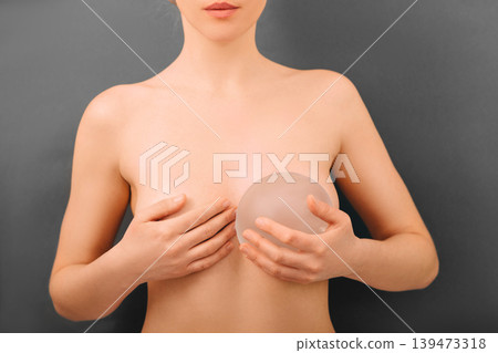 woman holding breast silicone implants near the breast. Augmentation breast size, breast Surgery. woman holding breast silicone implants near the breast. Augmentation breast size, breast Surgery. 139473318