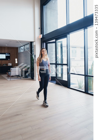 Young Woman Cruising On Skateboard Indoors Past Large Windows And Seating, Flowing Motion On Hardwood Floor With Relaxed Expression, Balancing Movement And Leisure In Contemporary Lobby Young Woman Cruising On Skateboard Indoors Past Large Windows And Seating, Flowing Motion On Hardwood Floor With Relaxed Expression, Balancing Movement And Leisure In Contemporary Lobby 139473335