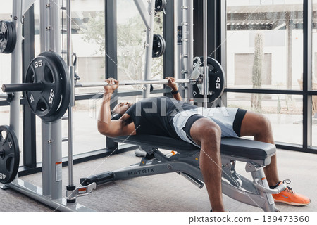 Strong Lifter Effort. Dedicated Athlete Performing Heavy Barbell Push With Determination. Serious Competitor Executing Fullrange Heavy Bench Press Under Intense Focus And Gym Ambiance Strong Lifter Effort. Dedicated Athlete Performing Heavy Barbell Push With Determination. Serious Competitor Executing Fullrange Heavy Bench Press Under Intense Focus And Gym Ambiance 139473360