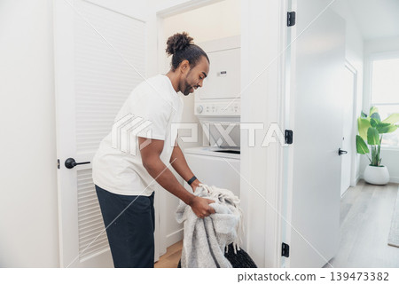 Black Man Folding Laundry In Small Laundry Alcove, Soft Natural Light, Towels And Clothing Neatly Stacked, Mindful Household Routine, Efficient Movement And Serene Domestic Atmosphere Black Man Folding Laundry In Small Laundry Alcove, Soft Natural Light, Towels And Clothing Neatly Stacked, Mindful Household Routine, Efficient Movement And Serene Domestic Atmosphere 139473382
