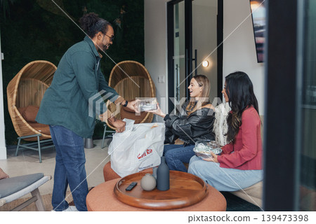 Driver Hands Food To Customer. Courier Passing Packaged Meals To Customer At Entrance Door. Delivery Personnel Exchanges Food Packages With Seated Customer In Cozy Indoor Setting Driver Hands Food To Customer. Courier Passing Packaged Meals To Customer At Entrance Door. Delivery Personnel Exchanges Food Packages With Seated Customer In Cozy Indoor Setting 139473398