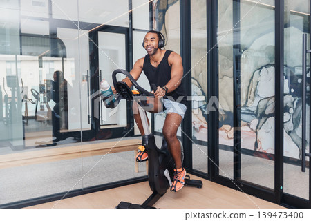 Preparing For Intense Cycling Workout. Man Calibrating Stationary Bike Before Exercise. Individual Finetuning Indoor Spinning Bike Parameters To Ensure Optimal Performance And Safety Preparing For Intense Cycling Workout. Man Calibrating Stationary Bike Before Exercise. Individual Finetuning Indoor Spinning Bike Parameters To Ensure Optimal Performance And Safety 139473400