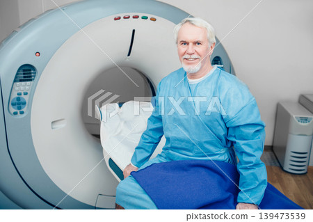 senior man sitting on scanner table. waiting for CT scan senior man sitting on scanner table. waiting for CT scan 139473539