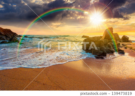 sunset over huge stones on the sandy beach. wonderful holiday season background at the sea. clouds on the blue sky above horizon. view of waves washing the shore. weather with rainbow sunset over huge stones on the sandy beach. wonderful holiday season background at the sea. clouds on the blue sky above horizon. view of waves washing the shore. weather with rainbow 139473819