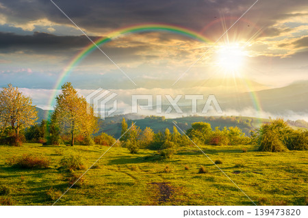sunset over carpathian mountain landscape with fog. outdoor adventure image for stunning view of meadow. mountain field and rolling countryside valley. cloudy sky with rainbow for background sunset over carpathian mountain landscape with fog. outdoor adventure image for stunning view of meadow. mountain field and rolling countryside valley. cloudy sky with rainbow for background 139473820