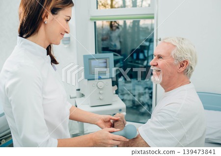 physiotherapist using ultrasound machine on hand of client in clinic. Physiotherapeutic treatment physiotherapist using ultrasound machine on hand of client in clinic. Physiotherapeutic treatment 139473841