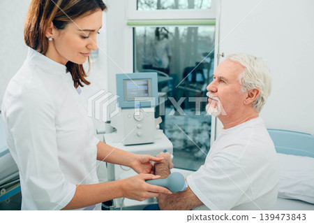 physiotherapist using ultrasound machine on hand of client in clinic. Physiotherapeutic treatment physiotherapist using ultrasound machine on hand of client in clinic. Physiotherapeutic treatment 139473843