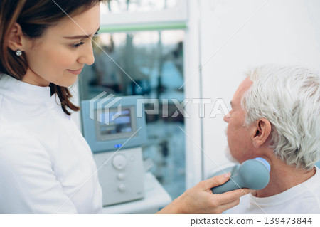 physiotherapist using ultrasound machine on neck of client in clinic. Physiotherapeutic treatment physiotherapist using ultrasound machine on neck of client in clinic. Physiotherapeutic treatment 139473844