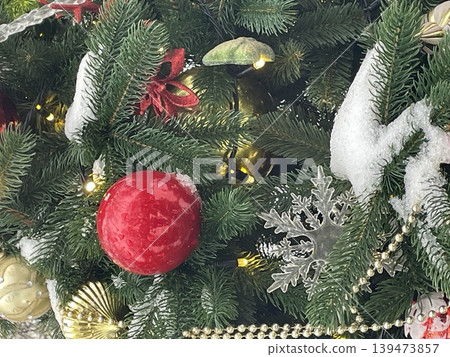 Christmas tree branches with snow, ornaments, and lights as festive holiday background Christmas tree branches with snow, ornaments, and lights as festive holiday background 139473857