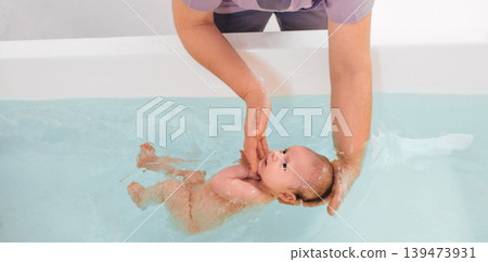 teaches infant baby to swim. Aquatic therapy for infant baby 139473931