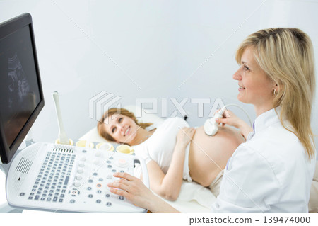 Pregnant woman having sonogram at clinic. pregnant patient ultrasound exam Pregnant woman having sonogram at clinic. pregnant patient ultrasound exam 139474000