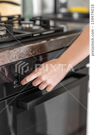 Hand Turning Oven Control in Modern Kitchen 139474018