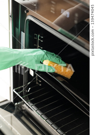 Cleaning the inside of the oven with a sponge and glove, removing grease in a modern kitchen. 139474045