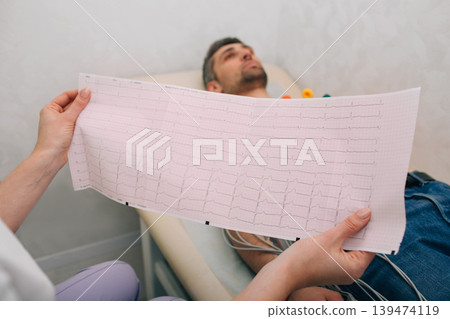 patient getting heart rate monitored at hospital. Close-up Of Ecg Report patient getting heart rate monitored at hospital. Close-up Of Ecg Report 139474119