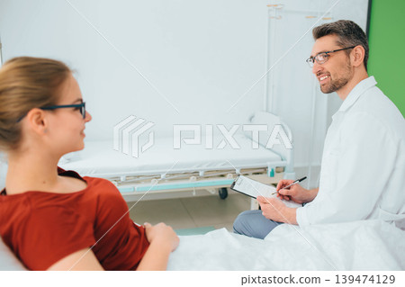 Male doctor talking to a smiling patient lying in a hospital bed Male doctor talking to a smiling patient lying in a hospital bed 139474129