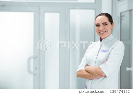 Portrait smiling doctor, standing at hospital corridor Portrait smiling doctor, standing at hospital corridor 139474152