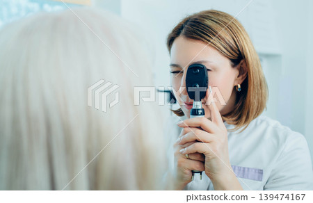 Doctor Optometrist examining senior patient's eyes with special eye equipment 139474167